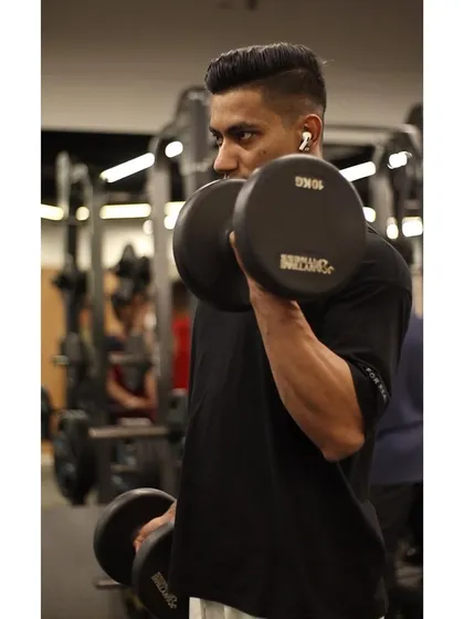 A member performs alternating dumbbell bicep curls, focusing on proper form to maximize muscle growth and avoid using momentum.