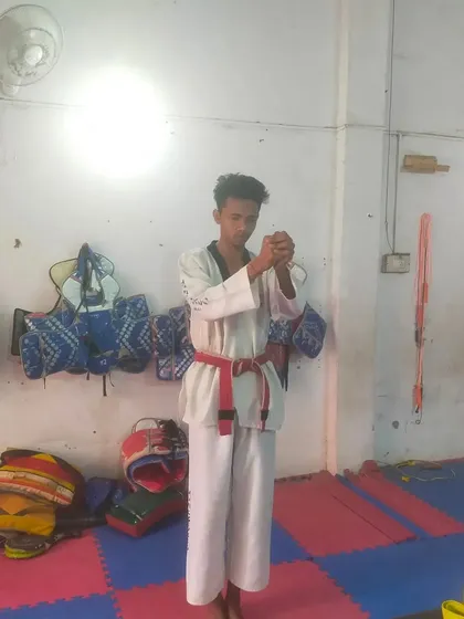 A red belt student prepares to demonstrate his board-breaking technique, a crucial part of senior belt tests.