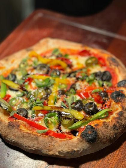 A freshly baked, wood-fired pizza topped with colourful bell peppers, olives, and jalapeños. Our pizza station is always a crowd-pleaser, serving up hot and delicious slices.
