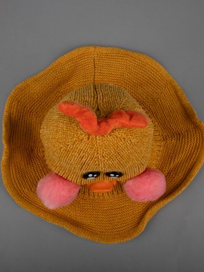 A top-down view of a mustard-yellow duck-themed knitted hat.