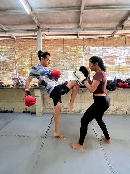 A member practicing her kicks with a partner during a HIIT class.