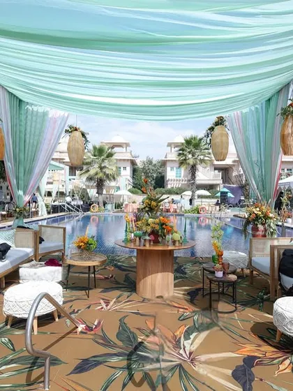 This poolside lounge was a tropical dream, with a canopy of aqua drapes, hanging woven lanterns, and comfortable seating, creating a relaxed and luxurious oasis.