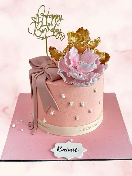 Pretty in pink for Bainu's birthday. This elegant cake features a large, handcrafted peony, a soft pink bow, and delicate pearl details.