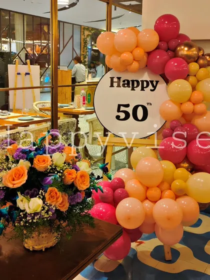 Celebrating a 50th birthday in style. This setup combines a vibrant balloon garland in sunset colors with a large, fresh floral arrangement, showing how I can create sophisticated and classy decor for important milestone events.