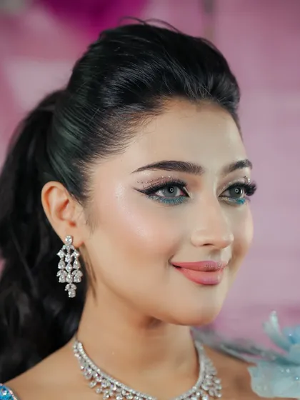 A dreamy, fairytale-inspired look. The makeup features a sharp winged liner with a pop of blue glitter and a soft pink lip.