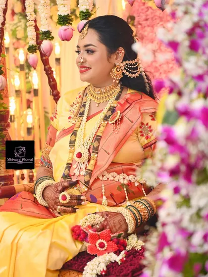 A beautiful portrait of a mom-to-be on her special day, adorned with a full floral jewellery set featuring red accents and a matching hand prop.
