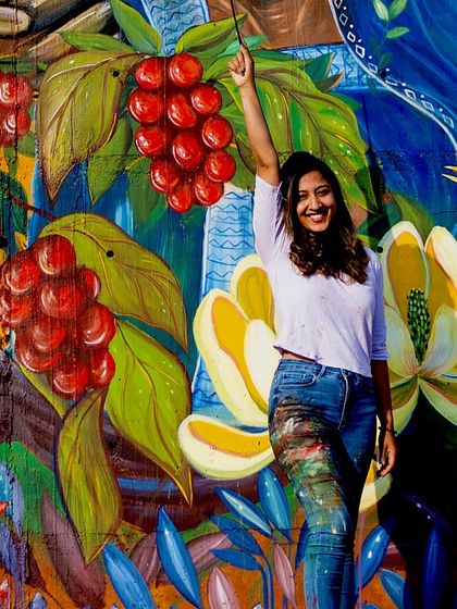 A joyful moment with the completed Coorg mural. My paint-splattered jeans are a testament to the energy and passion poured into this wall.