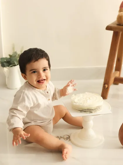 Ready for cake. This image captures the anticipation just before the cake smash begins. The simple, clean setup keeps the focus on the adorable birthday boy.