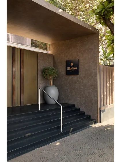 A close-up of the new entrance, showing the textured wall finish, modern signage, and the simple yet elegant handrail design.