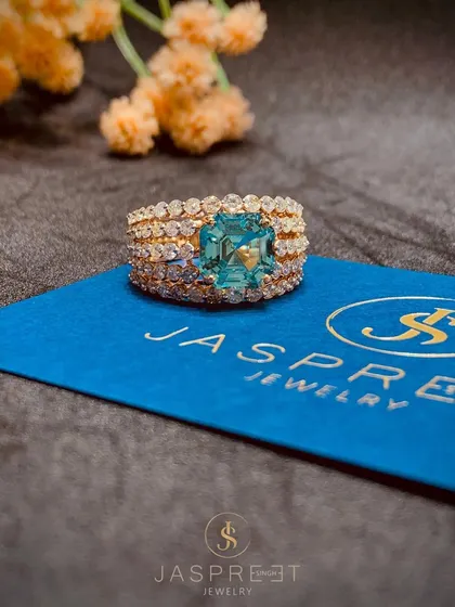 A truly exceptional ring featuring a large, emerald-cut blue gemstone set in a wide band of three rows of pavé diamonds. This piece is the epitome of bold, colorful luxury.