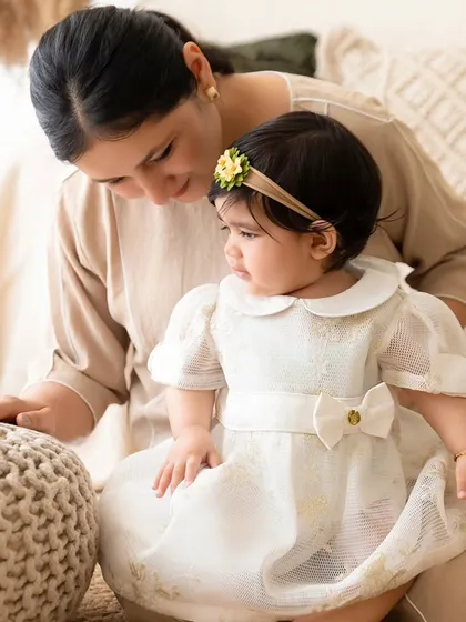 A mother and daughter interact in the boho studio setting. The textured props like the pouf add a cozy, tactile element to the photos.