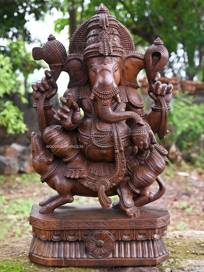 This 32.5-inch sculpture shows Lord Ganesha (Lambodara) seated on his vahana, the mooshak, while eating a modak. The wax brown finish highlights the intricate details of the deity and his divine vehicle.