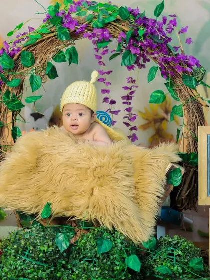 Baby Ishanvi in our snail costume, nestled in a basket decorated with greenery and a personalized nameplate. This shows a wider view of our themed newborn setups.