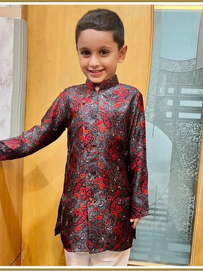 All smiles in his festive outfit. This little client looks dapper and happy in our red and black printed kurta, a perfect example of style crafted for cuteness and comfort.