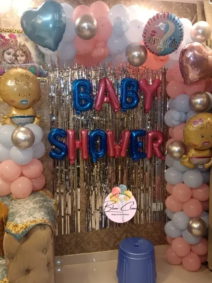 A gender reveal baby shower with a shimmer curtain backdrop and pillars of pink, blue, and silver balloons.