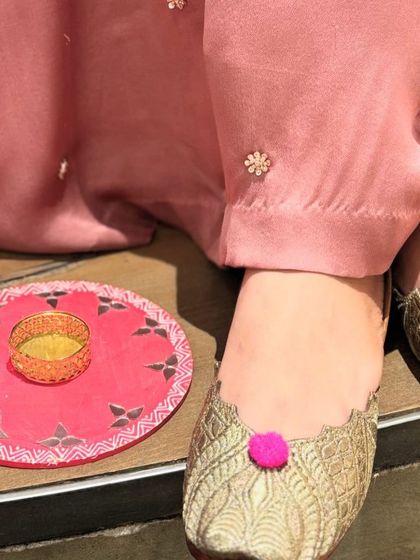 The perfect finishing touch. These gold woven juttis with a playful pink pom-pom add a pop of color and fun to this festive look.