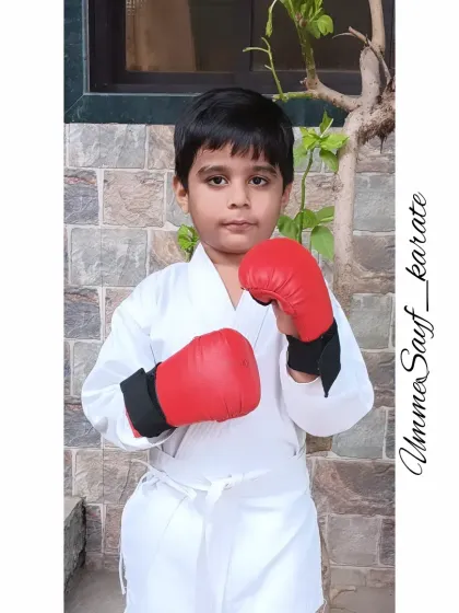 Let's learn the art of Karate. This young student is ready for kumite practice with his gloves on, showing a strong and focused stance. 🥋❤️