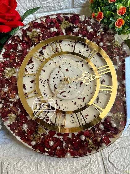 A slightly angled view of the clock, showing the texture of the preserved red rose petals and the shimmer of the gold flakes.