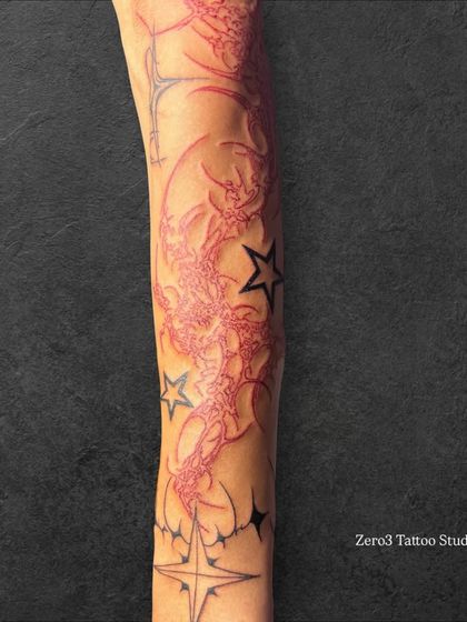 A detailed shot of a neo-tribal arm sleeve. The mix of red ink, black stars, and intricate patterns creates a powerful and modern piece of body art.