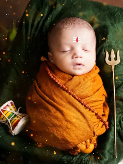 A serene portrait of a sleeping newborn in our Mahadev theme, with a damru and trishul. The soft lighting and magical effects add to the atmosphere.