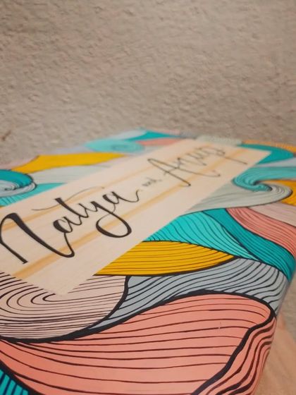 An angled view of the "Natya and Anup" plaque, showing the glossy finish that protects the intricate, hand-painted artwork.