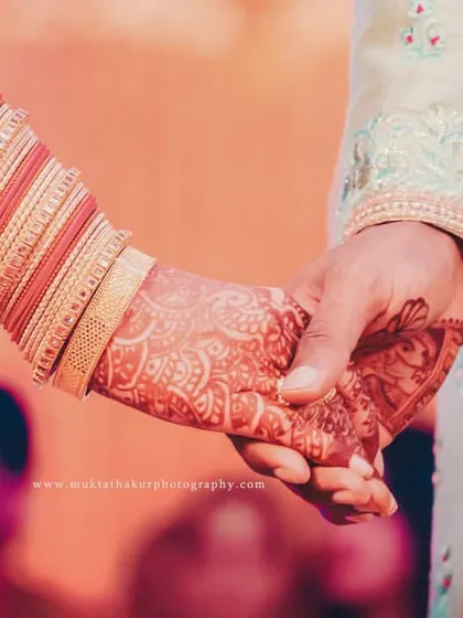 A simple, timeless gesture of holding hands during the wedding ceremony. This shot focuses on the details, from the intricate mehendi to the bridal bangles, symbolizing a new beginning.