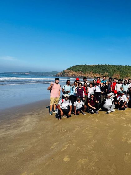 A large group photo on a pristine beach. The coastal trek is a great way to explore the hidden gems of Karnataka's shoreline.