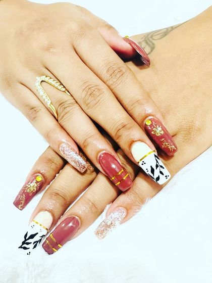 A beautiful, complex design on long coffin nails, featuring a mix of colors, glitter, and hand-painted leaf patterns.