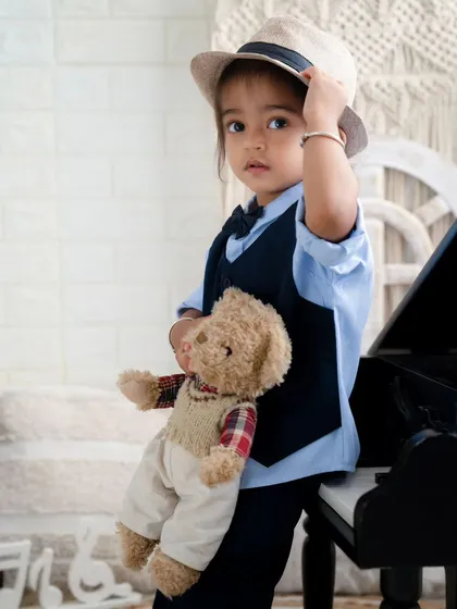 A dapper little gentleman with his teddy bear. This toddler looks so stylish and sweet posing by the miniature piano.