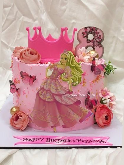 Welcome to the Barbie world. This pretty pink cake is perfect for an 8th birthday, featuring a Barbie cutout, a fondant crown, and delicate flowers and butterflies.
