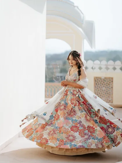 A bride twirls in her colorful floral lehenga during her Mehendi event in Jaipur. The movement and vibrant colors against the palace backdrop create a stunning, joyful portrait.