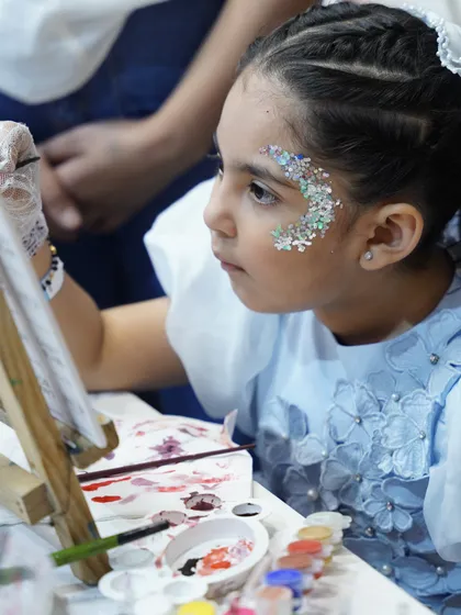 A young artist gets her face painted with glitter, adding a touch of sparkle to the party. We offer fun activities like face painting to enhance the celebration.