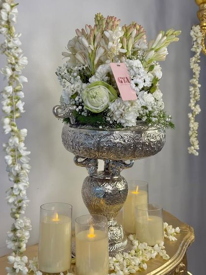 This shot includes traditional jasmine garlands alongside the silver urli, adding another layer of fragrance and festive charm to the decor.