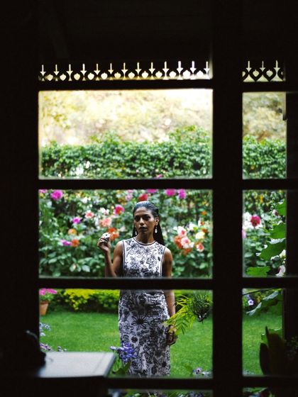 Anasuya Sengupta framed by a window, looking out onto a garden. This shot creates a sense of story and introspection, as if we are peeking into a private moment.