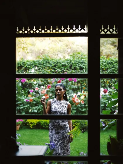 Anasuya Sengupta framed by a window, looking out onto a garden. This shot creates a sense of story and introspection, as if we are peeking into a private moment.