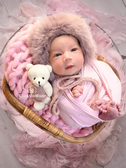Here is the same baby girl, now awake and curious, wearing an adorable furry hood and posing with her teddy bear companion.