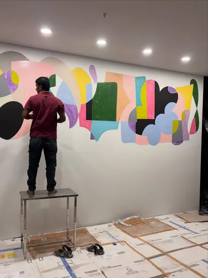 My team member working on the large-scale abstract mural for a commercial space. This image shows the physical effort and scale involved in bringing a 42-foot artwork to life.