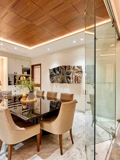 Our version of an elegant dining room, viewed through a glass partition. The design blends the warmth of a wooden ceiling and plush chairs with the glam of a polished marble floor and a modern art installation.