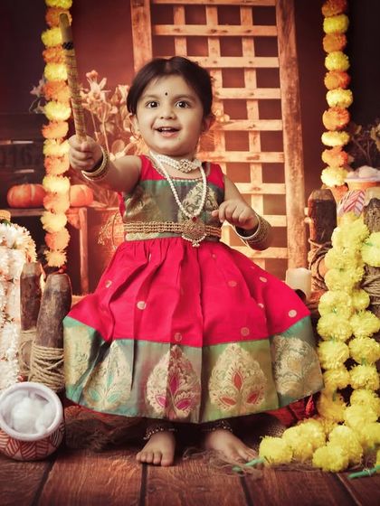 This little girl looks radiant dressed as Radha, with a playful expression. Our Radha-themed shoots are filled with color, flowers, and joyful moments.