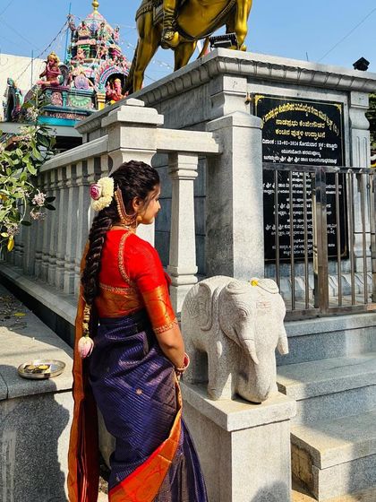 A back view showcasing the traditional hairstyle and the rich colors of the blue and red silk saree.