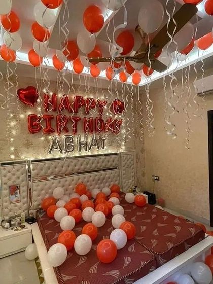 A bright and cheerful birthday room filled with red and white balloons, with a personalized "Happy Birthday Abhay" foil balloon sign.