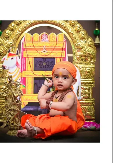 This little devotee, dressed in traditional orange attire, makes a playful gesture for the camera. The detailed shrine and props create a respectful and beautiful setting.