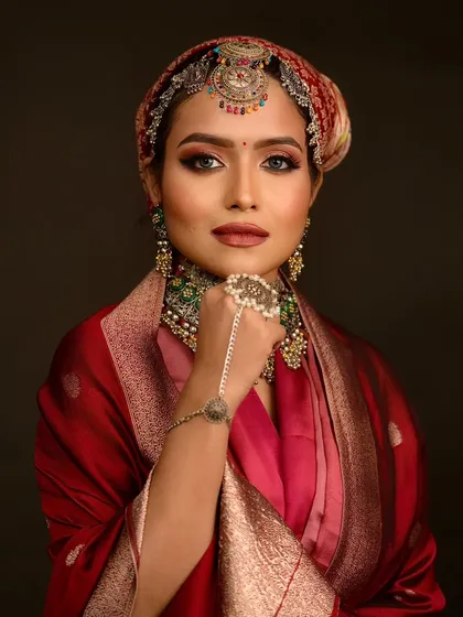 This pose highlights the unique hand jewelry and the warm tones in the makeup.