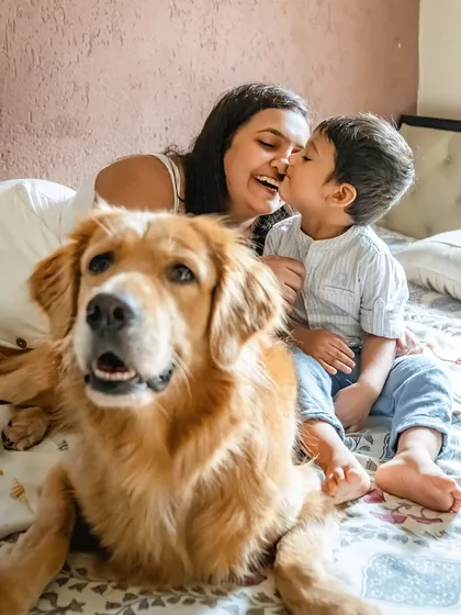 A happy photobomb from a furry family member! While Krishiv shares a sweet kiss with his mom, one of their Golden Retrievers makes sure to get in the frame. This is the beautiful, chaotic reality of life with kids and dogs.