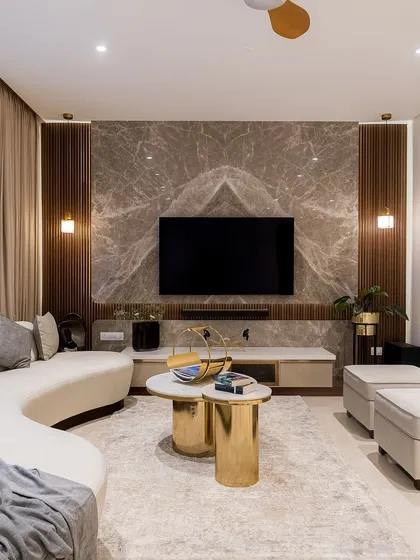 This living room is designed for connection and comfort. We combined a gracefully curved sofa with plush ottomans and striking gold coffee tables to create a space that is both inviting and sophisticated. The book-matched marble TV wall serves as a stunning focal point, demonstrating our commitment to using premium materials with artistic precision.