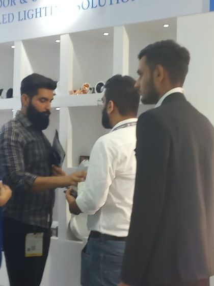 A group of visitors engages with an exhibitor, learning about the latest indoor and outdoor LED lighting solutions.