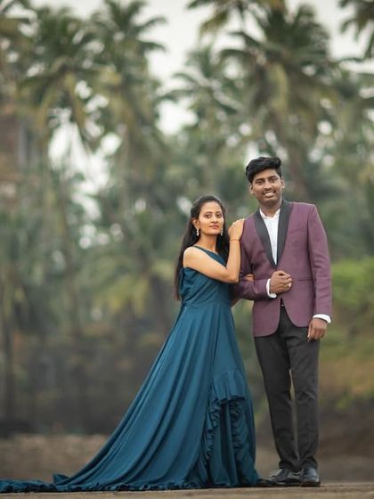 A stylish couple portrait in front of the iconic palm trees and fort ruins at Alibaug beach, blending glamour with a rustic setting.