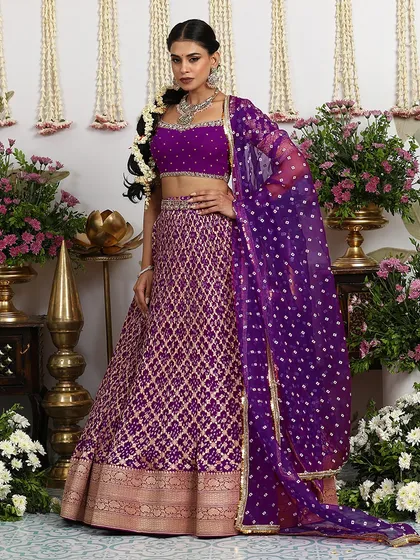 A magnificent purple Banarasi lehenga with gold zari embroidery, paired with a matching blouse and a Bandhani dupatta.