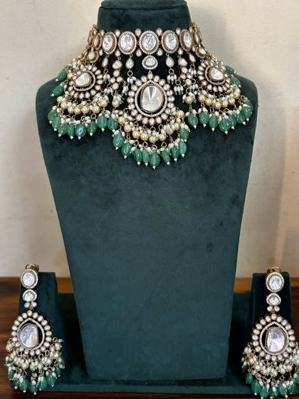 This Kundan necklace set for rent comes with matching chandbali earrings. The green beads and pearl accents give it a classic and elegant feel.