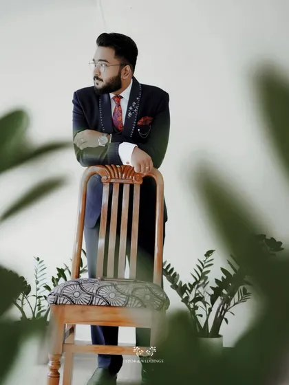 The groom leaning against a chair, looking stylish and composed in this modern, framed portrait.